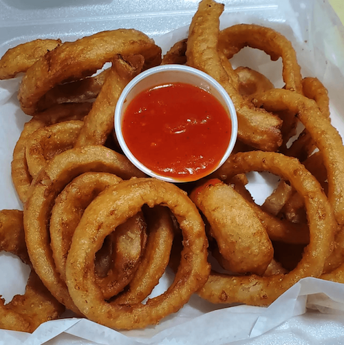 Onion rings surrounding a small container of ketchup
